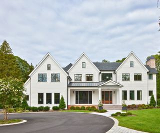 exterior of white clapboard home with trees and drive