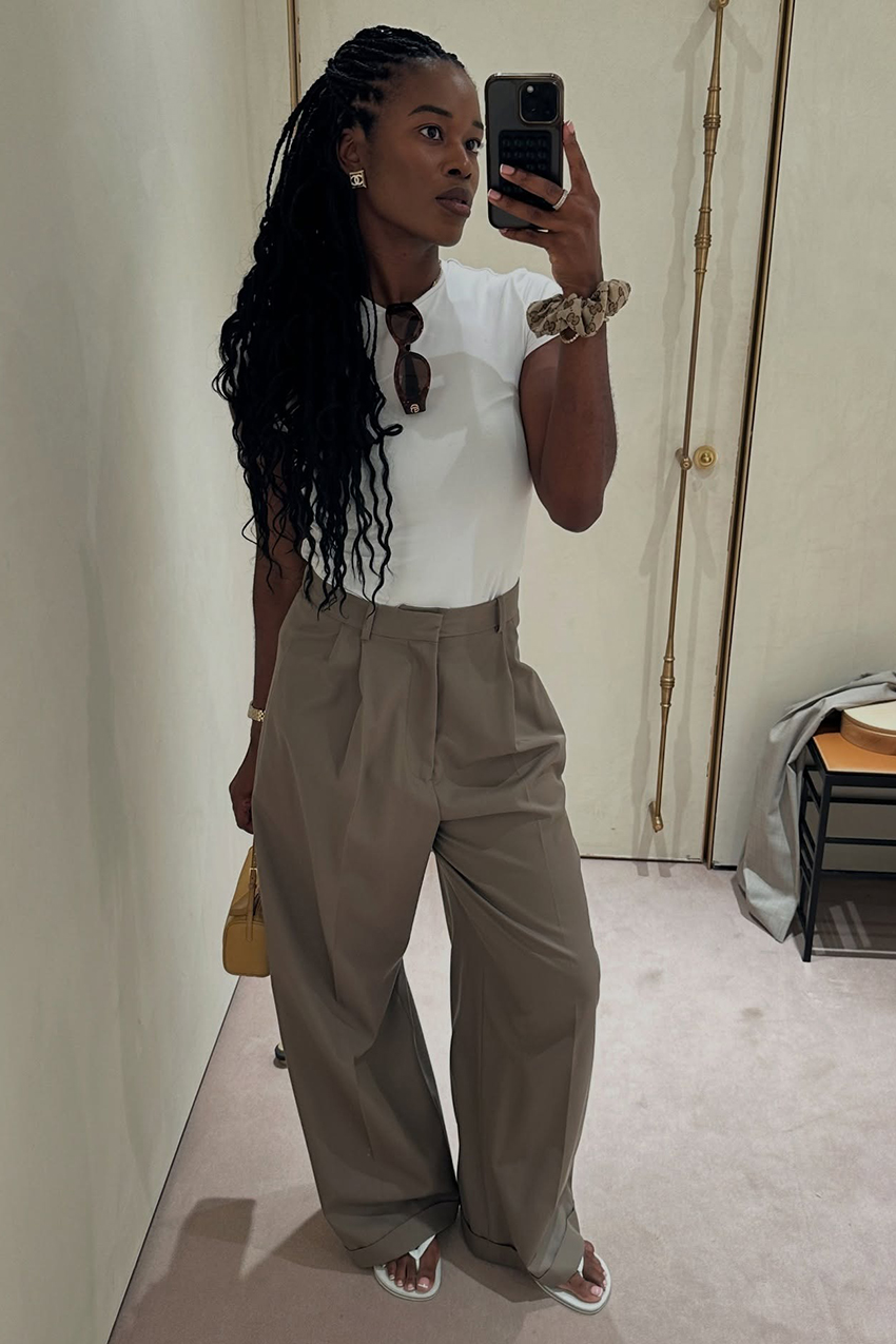 a woman wearing a white baby tee, khaki pants, and white flip flops