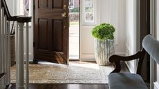 patterned runner in entryway with a wood front door and a large plant pot