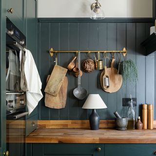 dark green kitchen with panelling and utensil rail