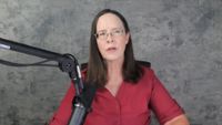 Female in pink shirt with mid length brown hair speaks into microphone