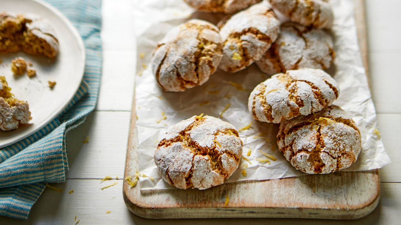 A selection of Pistachio and Lemon Amaretti on a sheet of parchement paper and a wooden board.