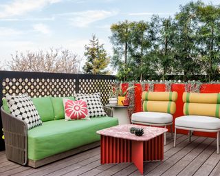 deck with green sofa, red table and white chairs with yellow and green backs