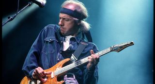 Mark Knopfler of Dire Straits wears his tennis sweat band and plays a fingerstyle solo on his Schecter S-style during a 1992 show in the Netherlands