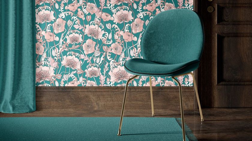 A bold, elegant hallway featuring teal and blush floral wallpaper with a dark wood skirting board. A teal velvet chair with brass legs and matching curtain adds modern sophistication.