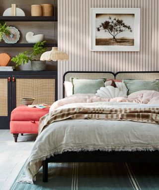 A bright and colorful bedroom with black shelves, striped wallpaper, rattan bed and blue rug