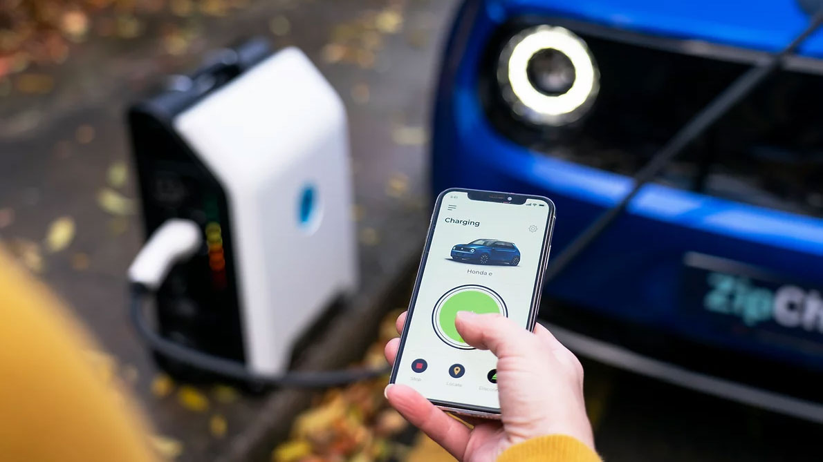 Close-up of phone app with charger and car in background