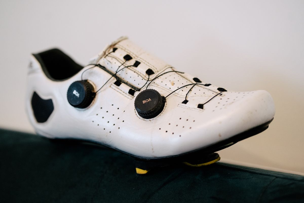 A white leather cycling shoe on a green sofa