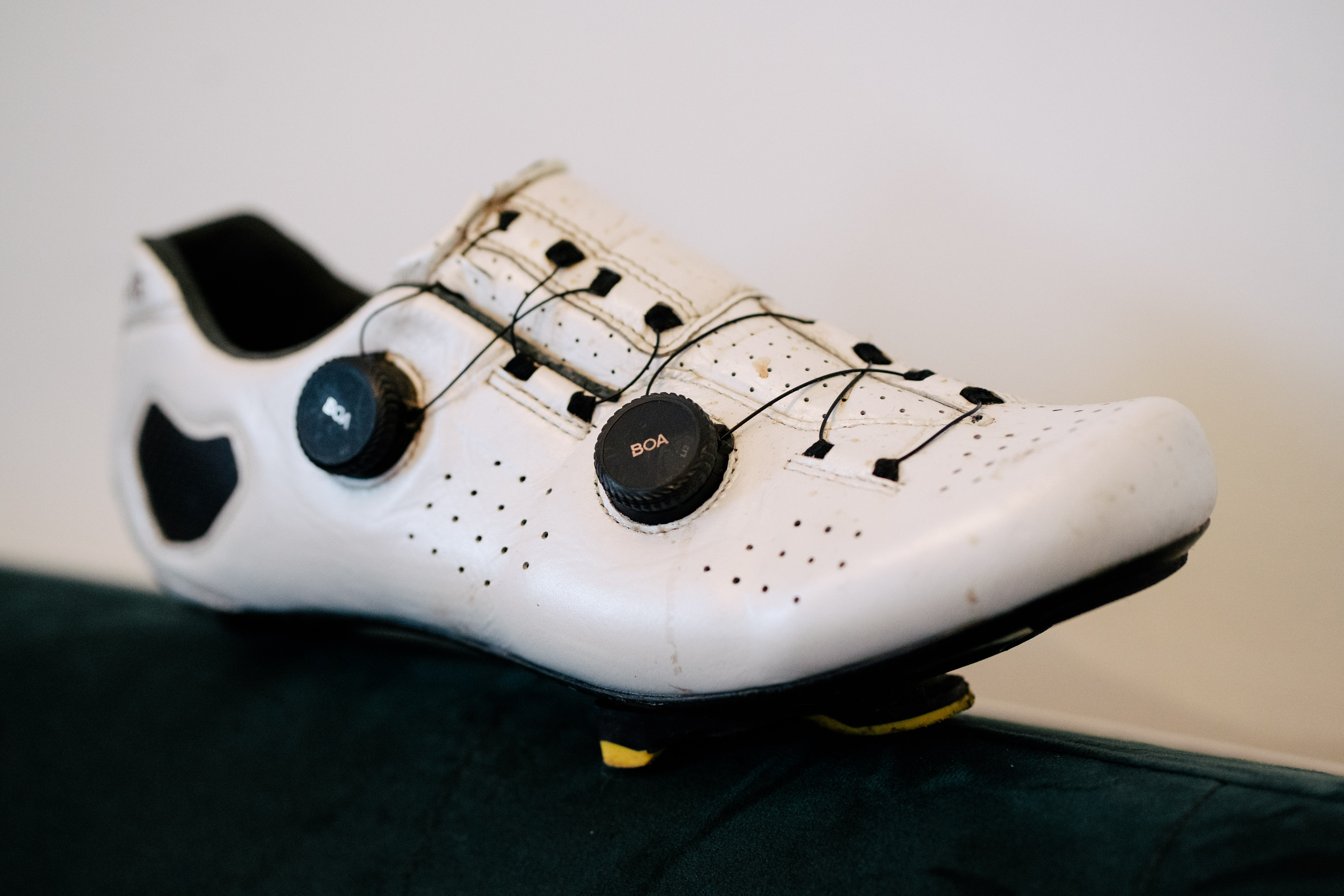 A white leather cycling shoe on a green sofa
