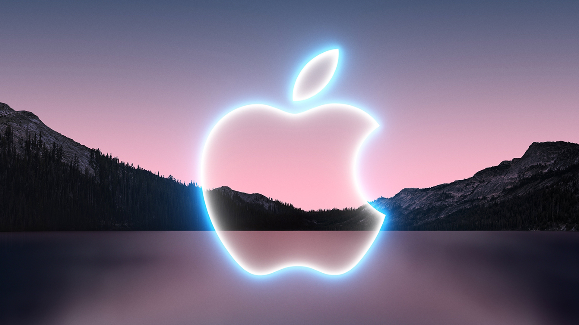 A glowing Apple logo in front of a mountainous backdrop.