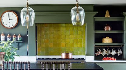 green kitchen with island, glass pendant lights and tiles
