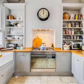 Kitchen with stove and oven, grey cupboards and wall shelves