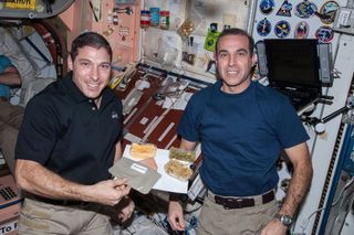 NASA astronauts Michael Hopkins (left) and Rick Mastracchio show off a spread of Thanksgiving dishes aboard the International Space Station in 2013.