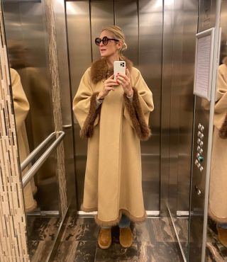 Actress Kelly Rutherford wearing brown Ugg boots, a tan coat with fur piping, and jeans