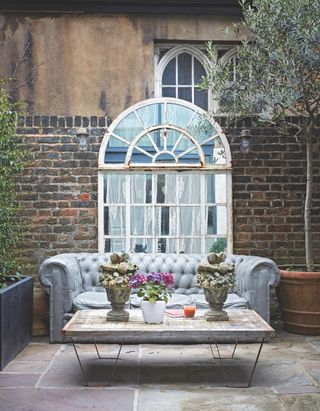 Small courtyard garden with sofa and large mirror