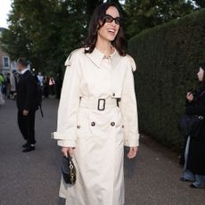 Alexa Chung wears a cream trench coat over semi-sheer tights and checked pointed-toe heels.