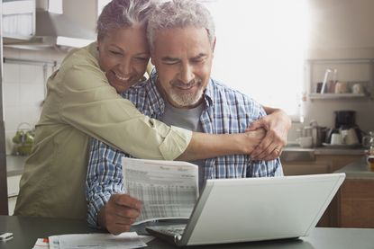 Smiling couple paying bills on laptop