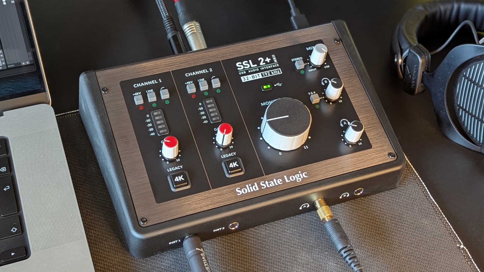 An SSL 2+ MKII audio interface on a desk with a laptop and studio headphones