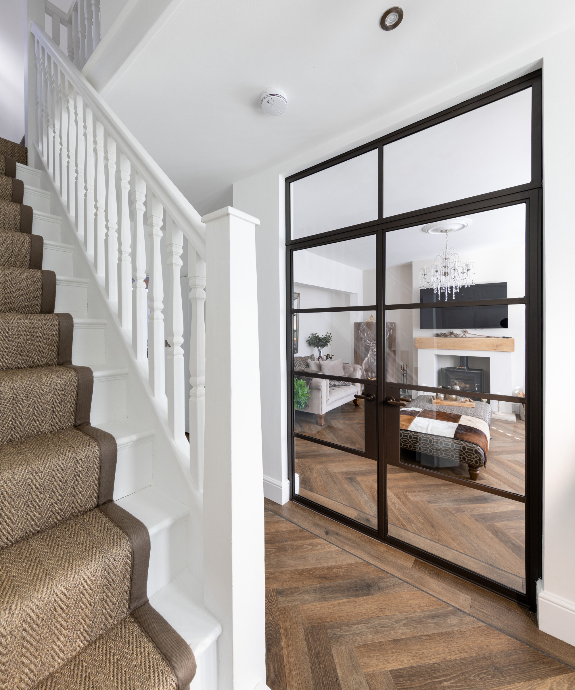 white wooden stairs with brown carpet runner and glazed doors off hallway leading into living room