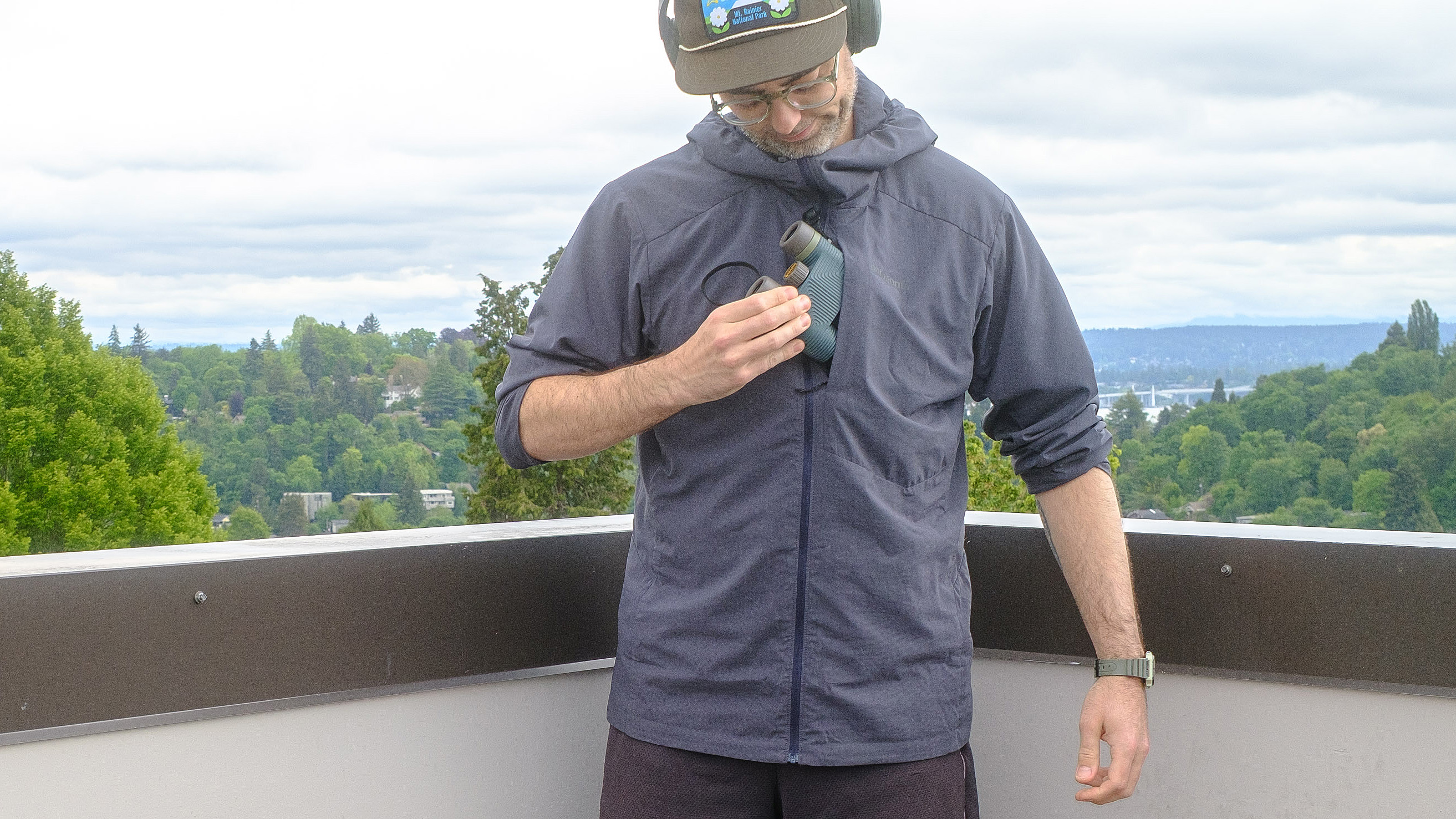 Senior writer Dan Bracaglia wearing the Patagonia Nano-Air Ultralight in grey/blue on the roof of his home in Seattle, Washington with trees and overcast skies in the distance
