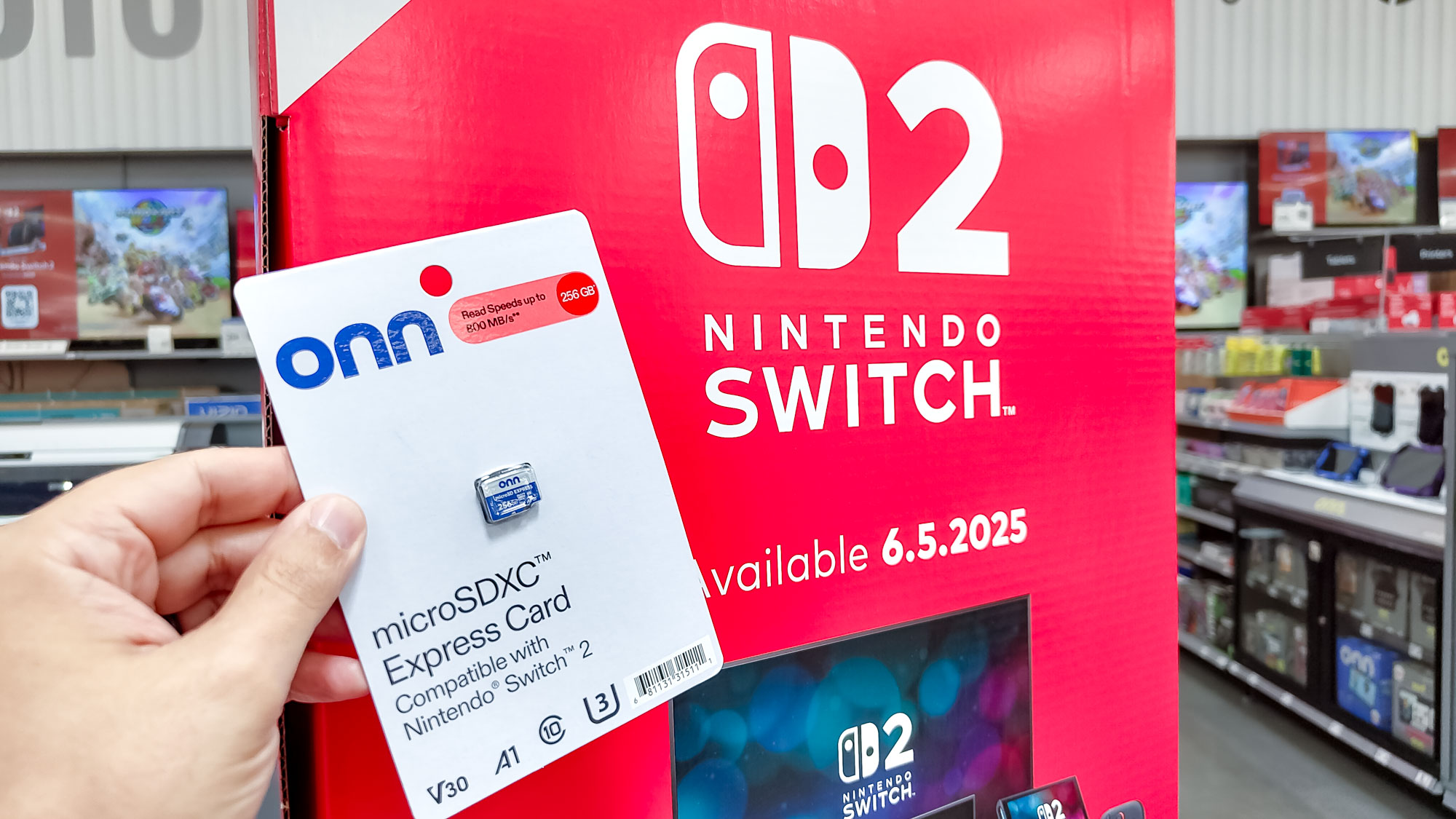 A person holding an Onn microSD Express card in front of a Nintendo Switch 2 floor display