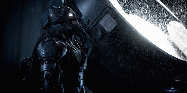 Armored Batman standing next to Batsignal