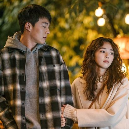 a girl holds a boy's arm while walking on a date in a still from a korean romance movie