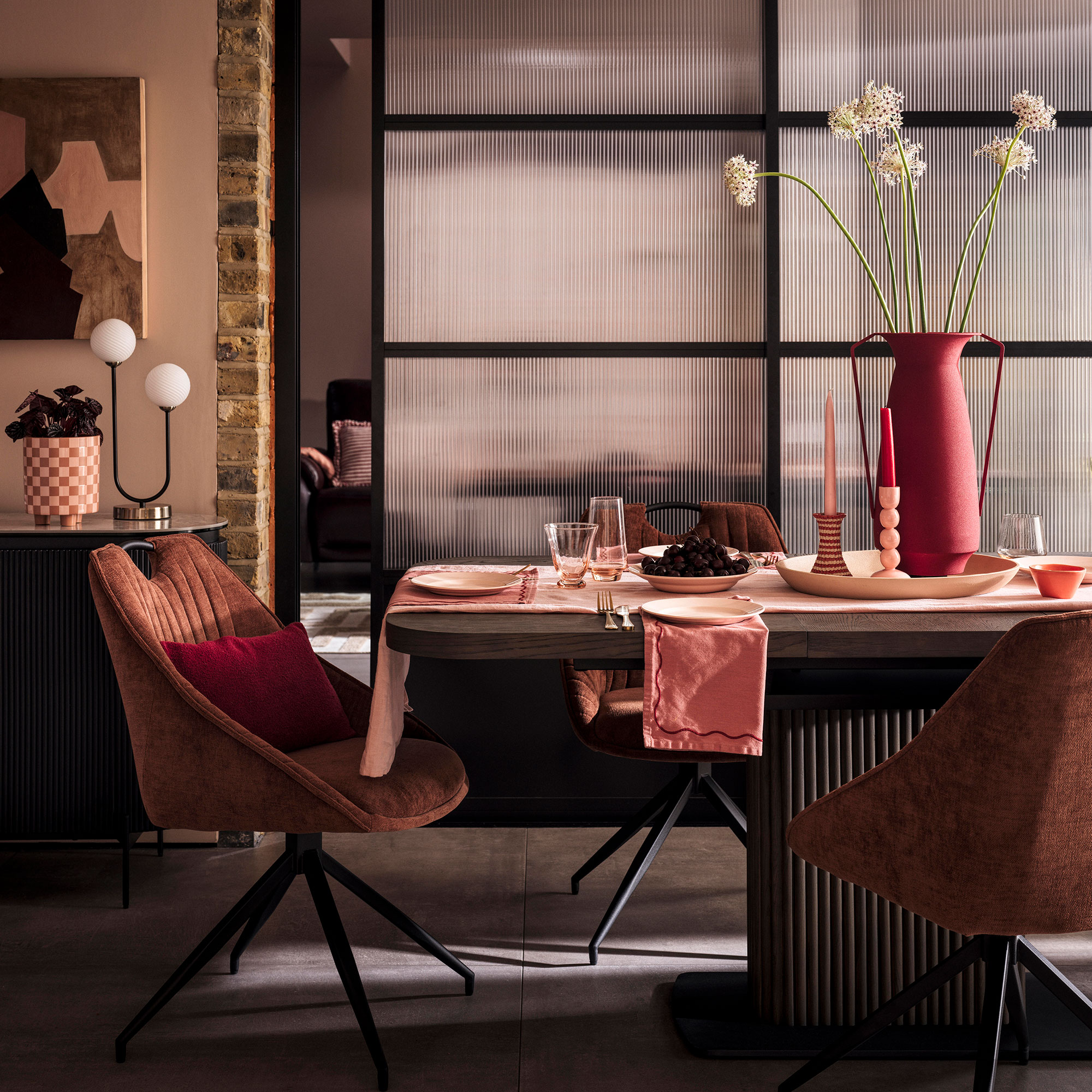 Dark wood dining table with red accessories and rust coloured upholstered dining chairs