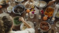 teenage girl having food while sitting at dining table during Thanksgiving