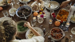 teenage girl having food while sitting at dining table during Thanksgiving