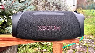 LG XBoom Go XG8T wireless speaker on wooden garden bench