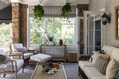 front porch sitting space with white canework sofas and chairs and hanging plants