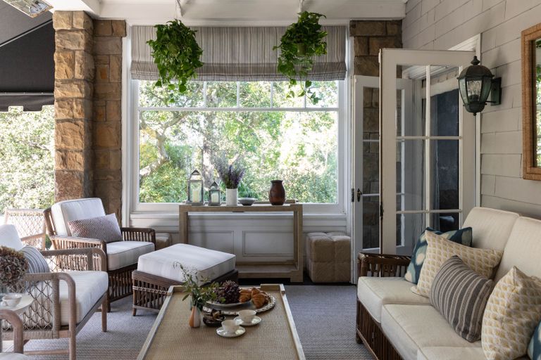 front porch sitting space with white canework sofas and chairs and hanging plants