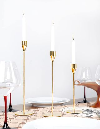 three gold candlesticks at different heights holding taper candles