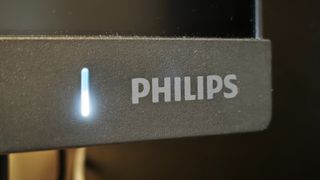 A black Philips Evnia 25M2N3200W monitor sitting on a wooden desk