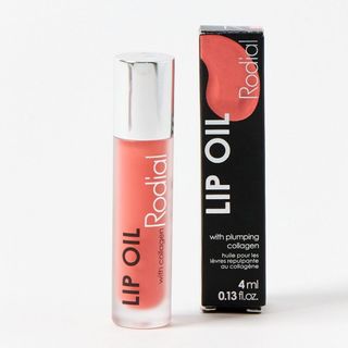 A bottle of Rodial Lip Oil alongside the box, pictured on a neutral background