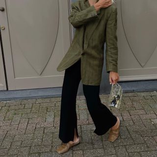 Linda Tol styles an olive green blazer with tan mules and black trousers.