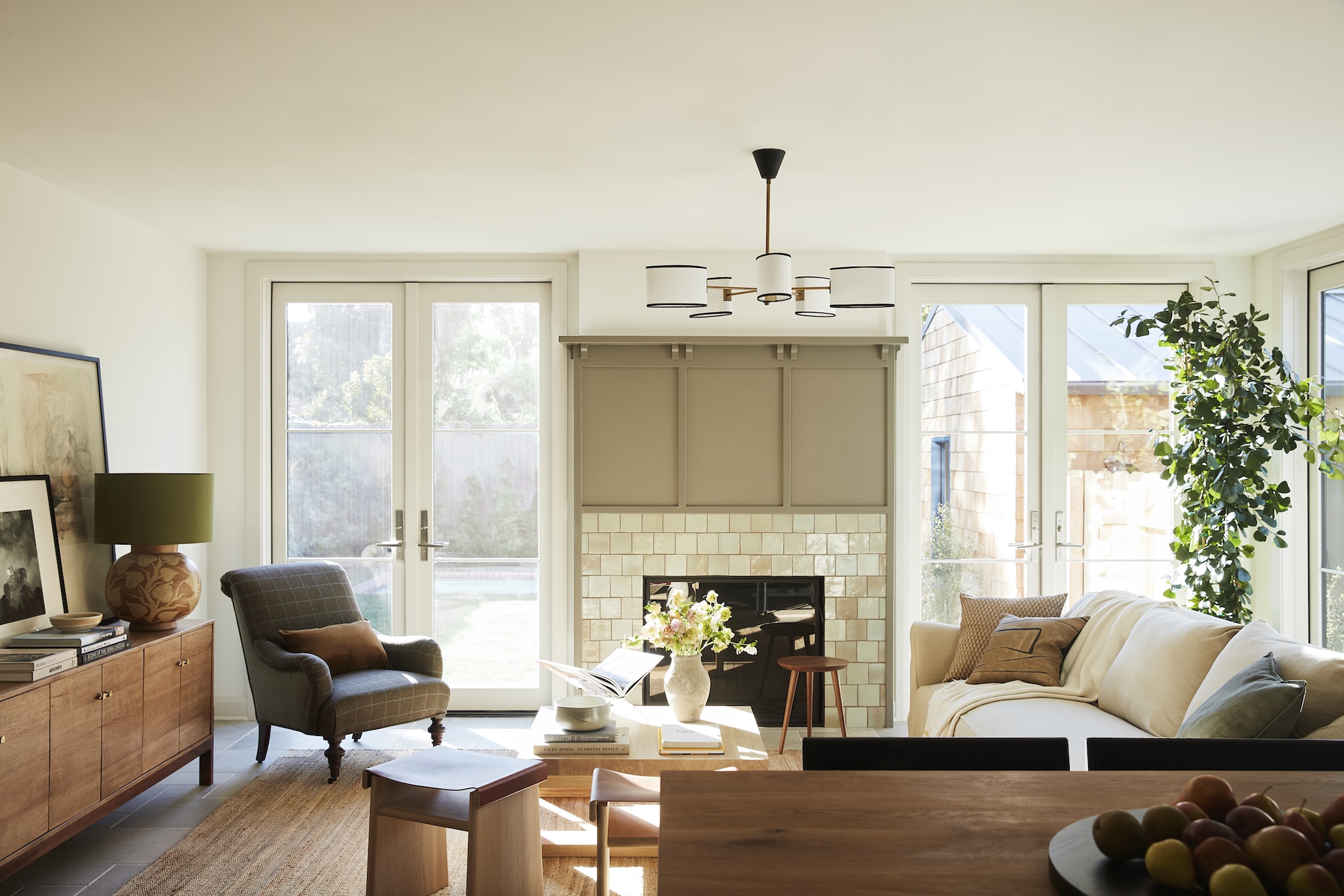 A modern traditional living room in neutral off whites and brown tones with a white tiles fireplace and panelling above