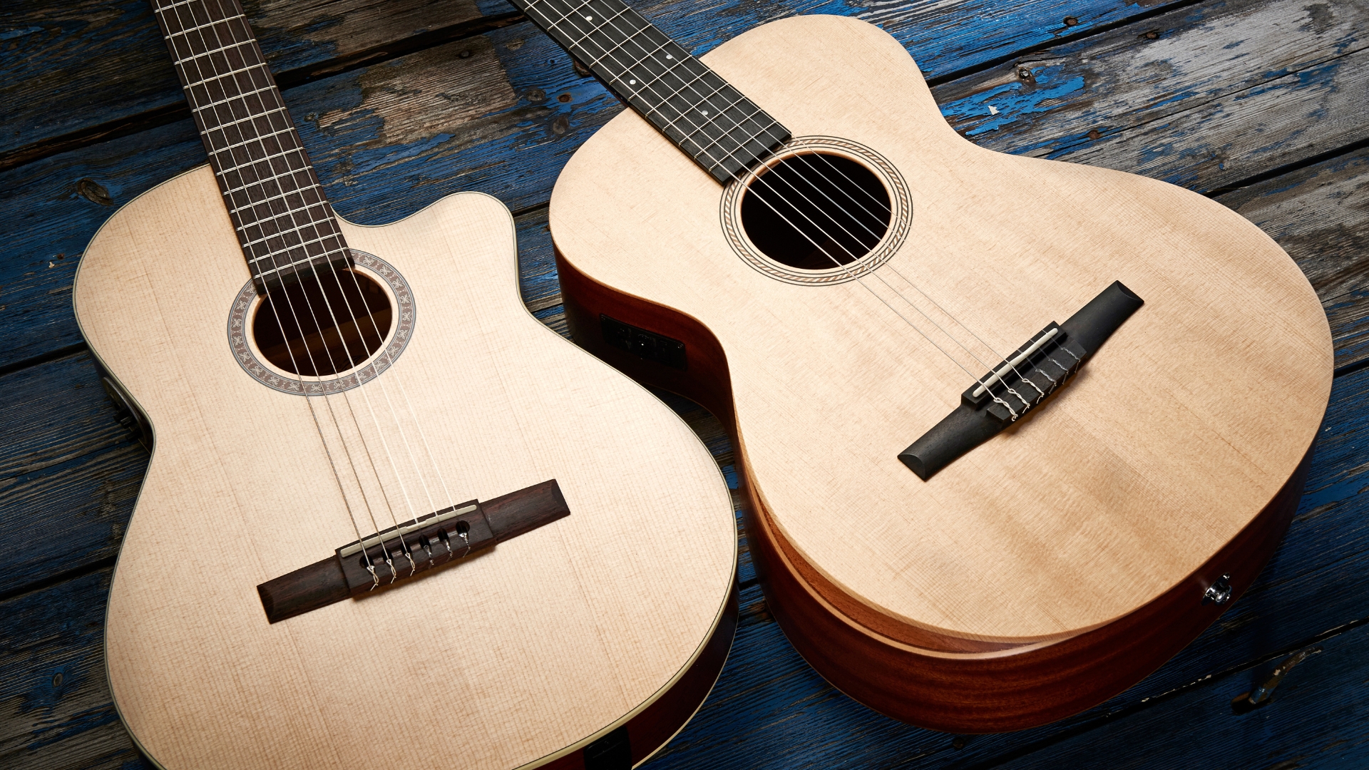Two Taylor classical guitars lying on a heavily worn blue wooden floor