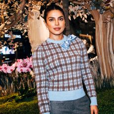 Woman wearing a checkered sweater with a slicked updo hairstyle smiling at the camera