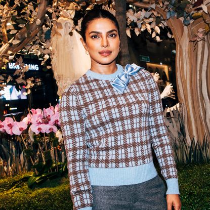 Woman wearing a checkered sweater with a slicked updo hairstyle smiling at the camera
