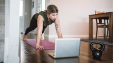 woman holds high plank at home 