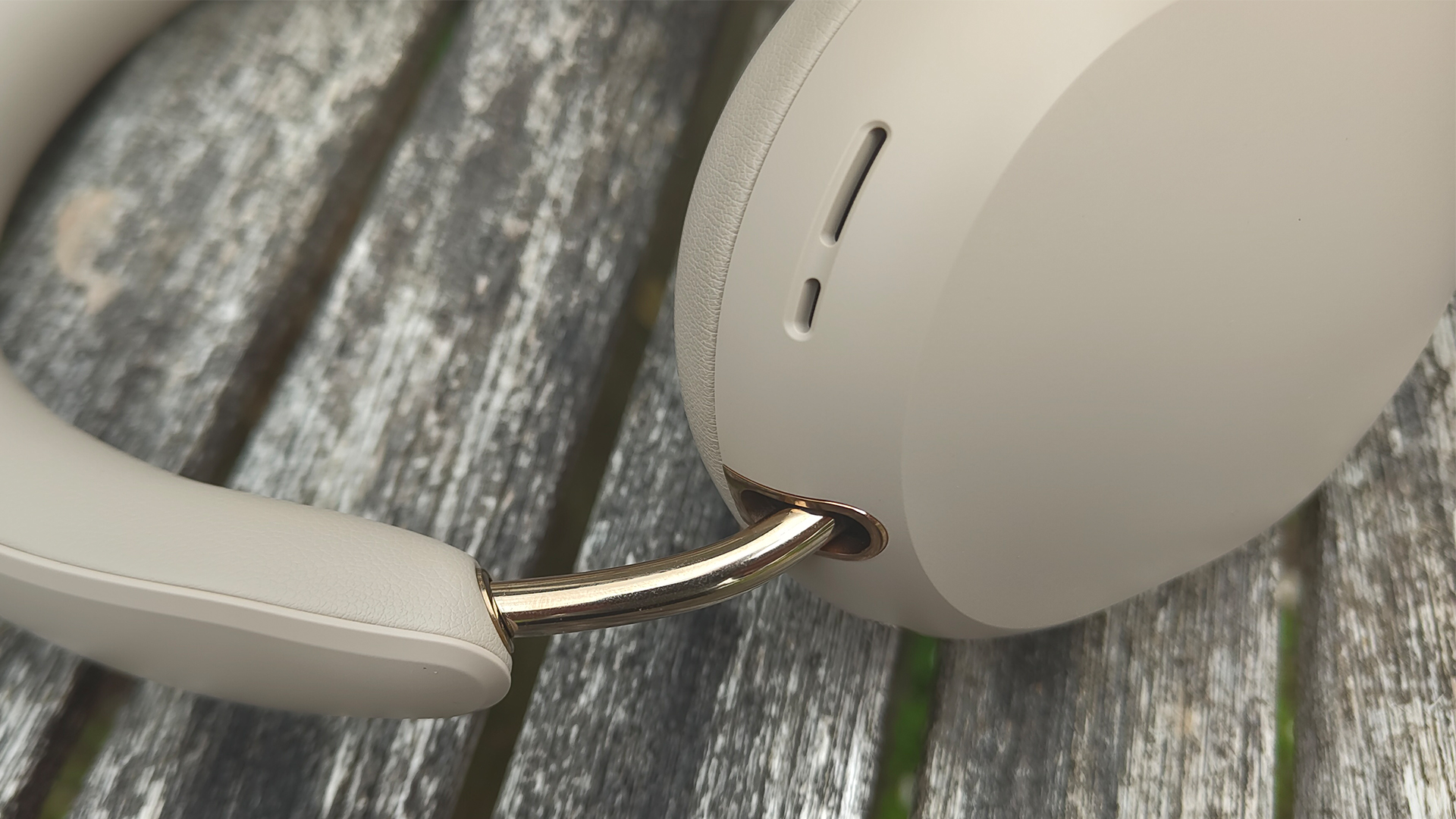 Sonos Ace Ultra wireless headphones on wooden slatted table, detail of one earcup and headband
