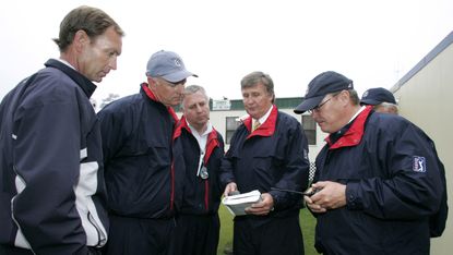 Golf Rules officials study a Rule Book