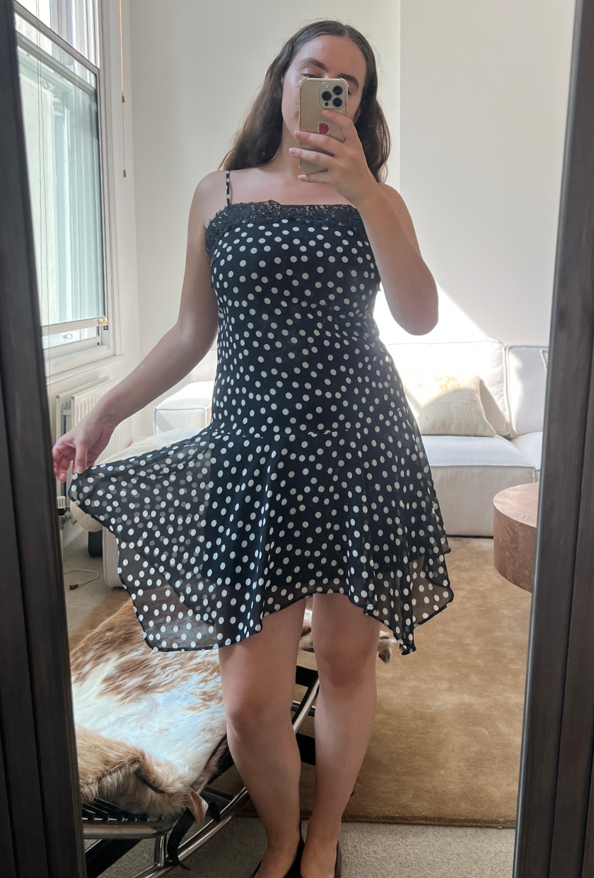 An image of Who What Wear UK fashion writer, Ava Gilchrist, wearing the viral M&S polka-dot lace-trim slip dress. She is a size M and wears it in a size 10.