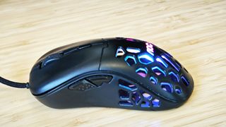 A black AOC GM510 gaming mouse with a hollow honeycomb structure and RGB lighting sitting on a desk