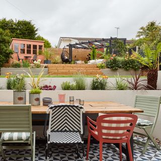 Outdoor dining area on terraced surrounded by raised beds