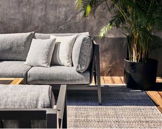 A black powder-coated aluminium outdoor sofa with padded grey seat cushions from Outer