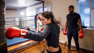 Woman punching heavy bag in boxing gym