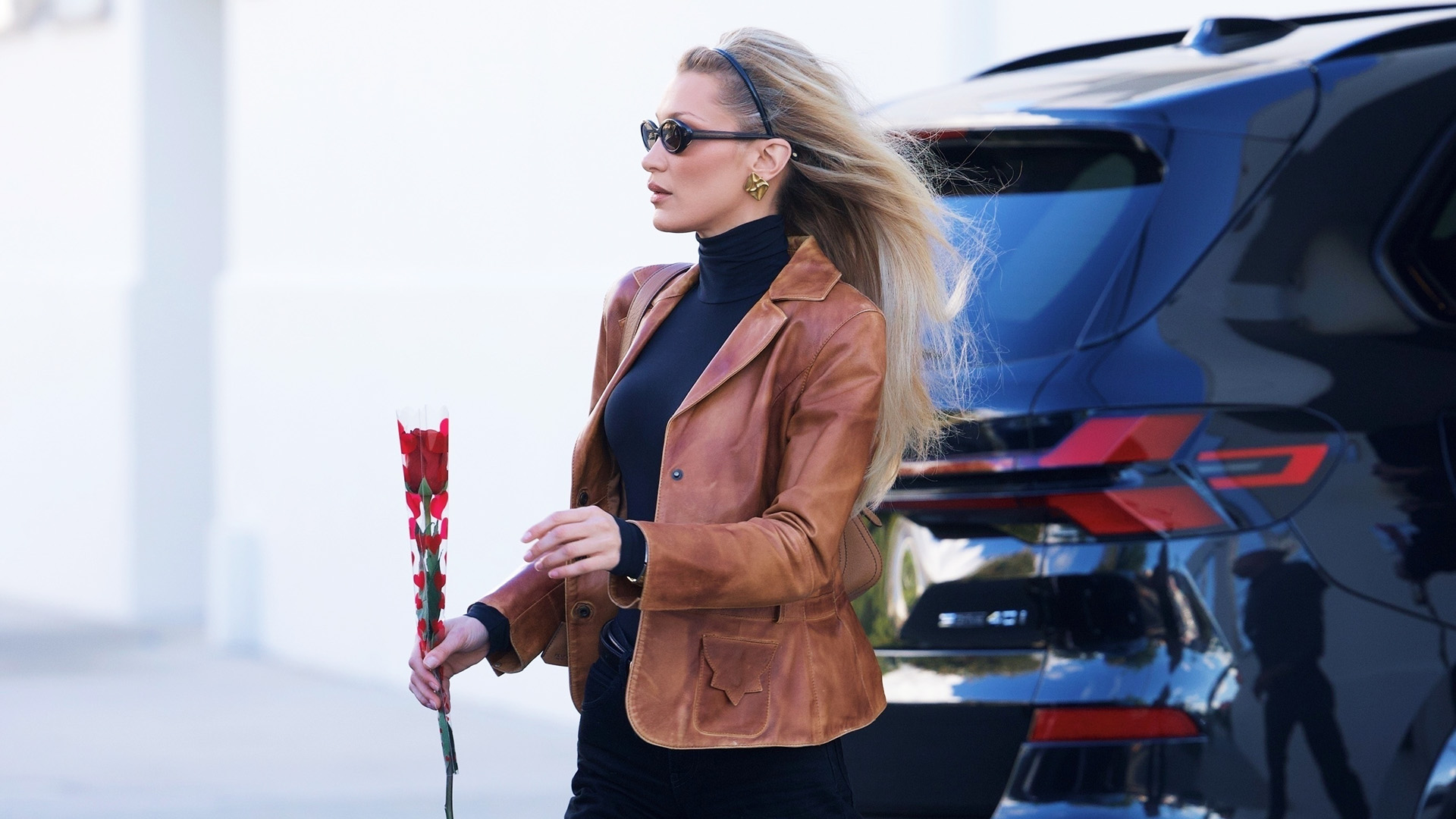 Bella Hadid wearing a brown leather jacket, black turtleneck, bootcut jeans, and block-heel boots